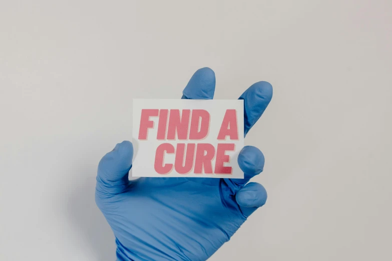a gloved hand holding a sign that says find a cure, by Julia Pishtar, trending on pexels, hurufiyya, neuroscience, pink and blue colour, cut out, restoration