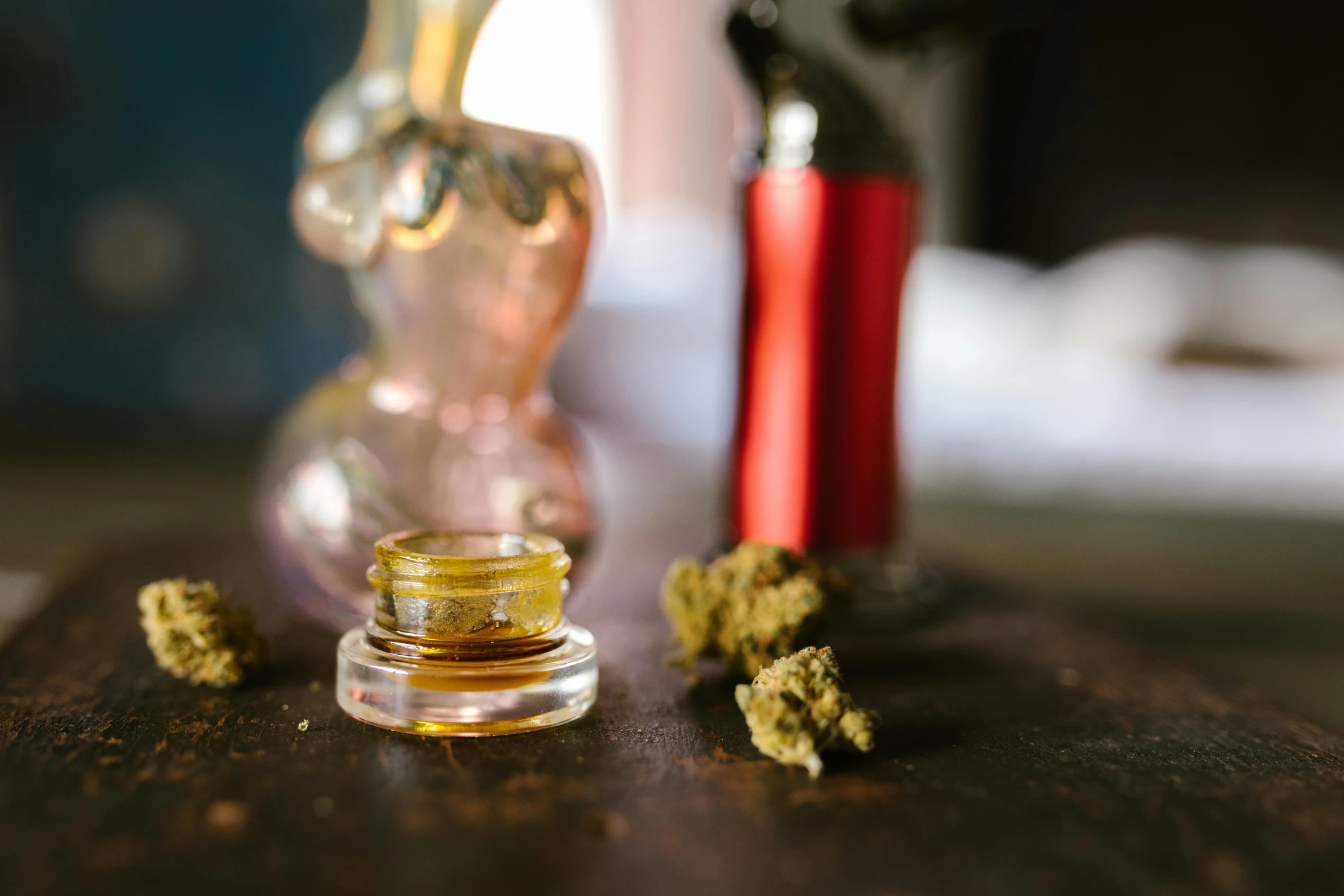 a glass bottle sitting on top of a wooden table, weed, detailed product image, various items, liquid gold