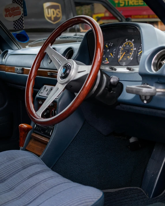 a close up of a steering wheel in a car, an album cover, unsplash, renaissance, mercedes and volkswagen, white and blue color scheme, 70s interior with arched windows, wooden trim