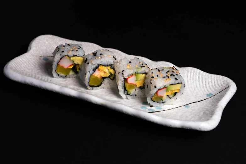 three sushi rolls on a plate on a black background, sōsaku hanga, square, avacado dream, 6 pack, speckled