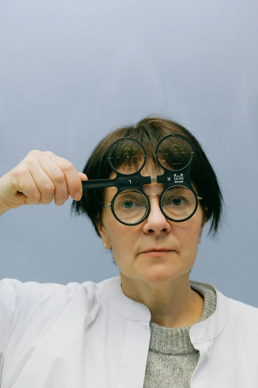 a woman holding a pair of scissors over her head, by Adam Marczyński, specimens in glasses, multiscopy, practical, black spot over left eye