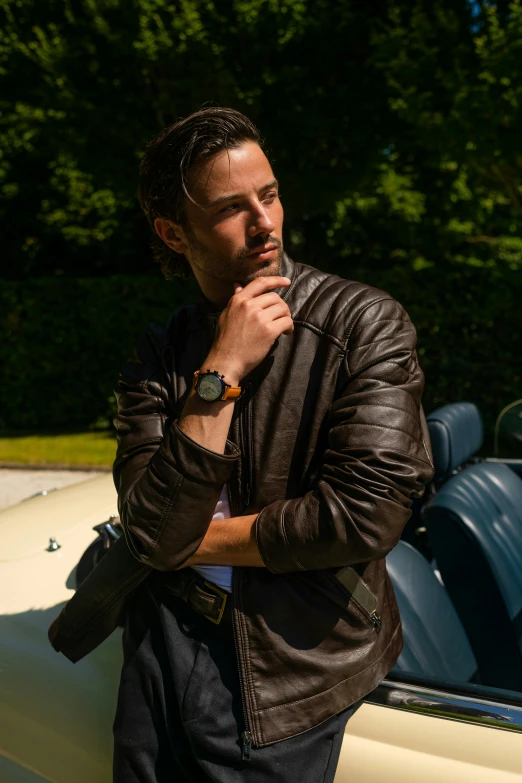 a man in a leather jacket standing next to a car, inspired by Harry Haenigsen, wearing a watch, brown, thumbnail, model pose