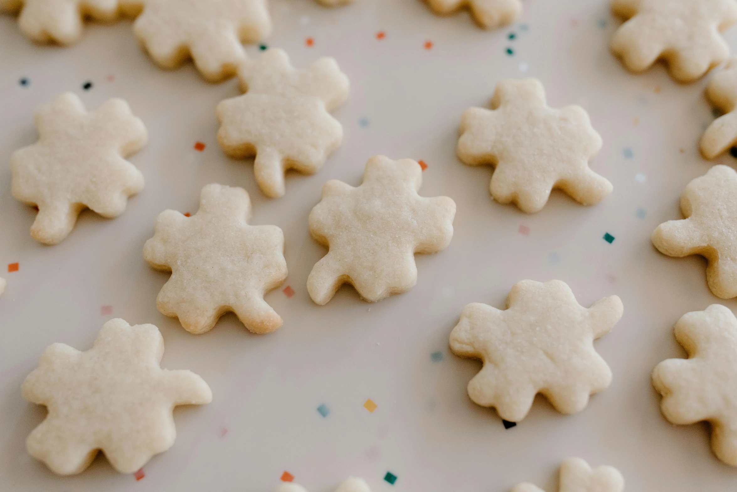 a white plate topped with cookies covered in frosting, a jigsaw puzzle, by Jessie Algie, trending on pexels, blurry, four leaf clover, siluettes, smol