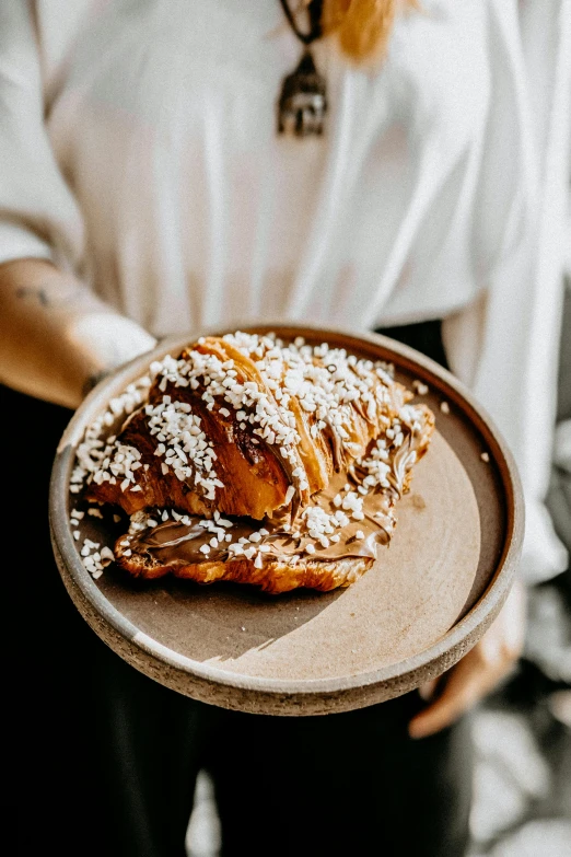 a person holding a plate with a pastry on it, nordic crown, gnarled, daily specials, far view