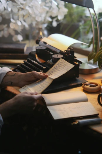 a person sitting at a desk with a typewriter, botanicals, warm glow, with notes, ignant