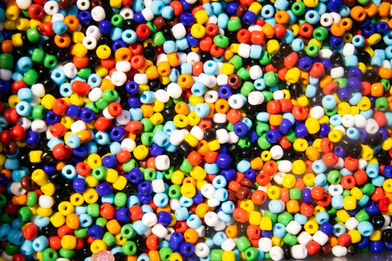 a pile of colorful beads sitting on top of a table, inspired by Alma Thomas, pexels, pointillism, seeds, seamless micro detail, vivid colors!!, plastic ceramic material