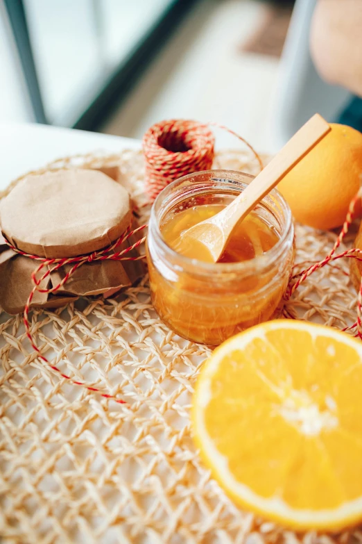 a table topped with orange slices and jars of honey, pexels contest winner, cloth wraps, strings, creamy, orange ray