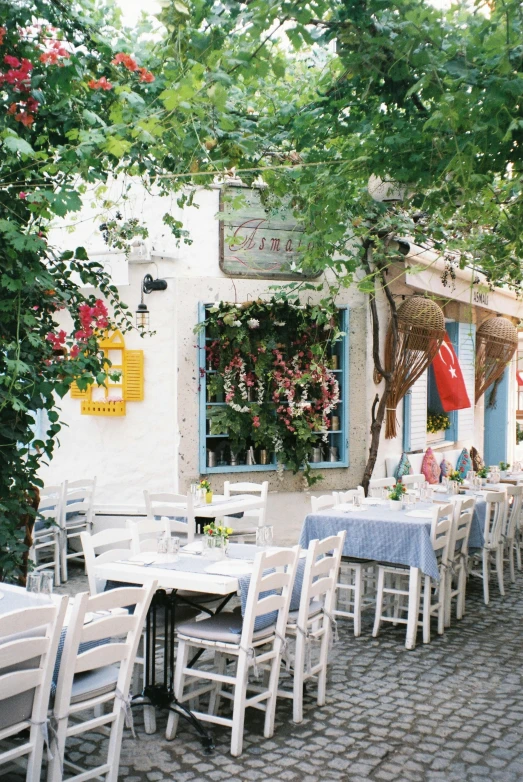 an outdoor dining area with tables and chairs, a photo, inspired by Theophanes the Greek, bustling, white, 1990s photograph, gif