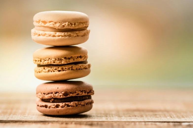 a stack of macarons sitting on top of a wooden table, three michelin star, thumbnail, brown, high-resolution