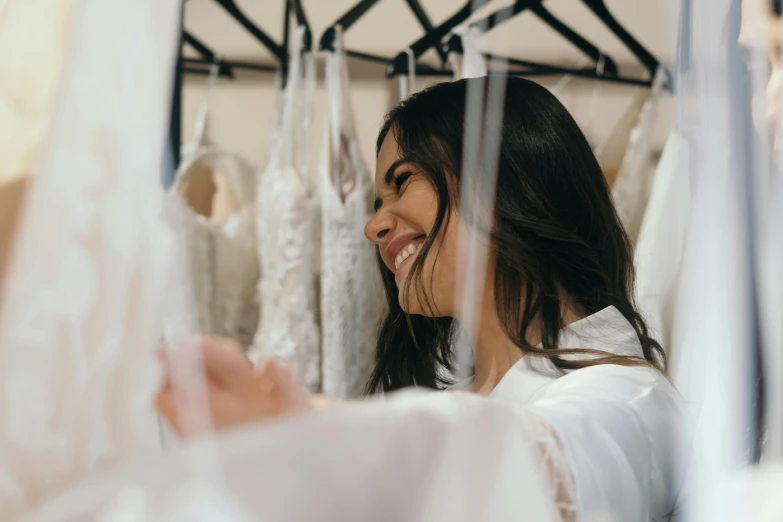 a woman standing in front of a rack of wedding dresses, pexels contest winner, happening, turning her head and smiling, pokimane, wearing white cloths, filling the frame