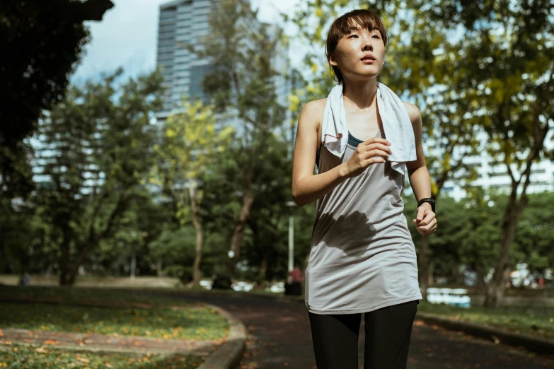 a woman running in a park with trees in the background, a portrait, inspired by Cheng Jiasui, pexels contest winner, happening, wearing : tanktop, malaysian, thumbnail, fashionable