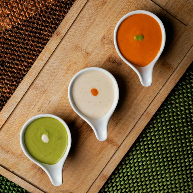 three bowls of soup sit on a cutting board, inspired by Ceferí Olivé, kewpie mayonnaise, green and orange theme, various colors, three michelin star