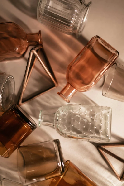 a bunch of empty bottles sitting on top of a table, a still life, inspired by Giorgio Morandi, trending on unsplash, small square glasses, reflections in copper, detailed product image, liquid translucent amber