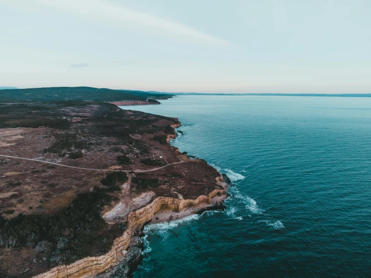 a large body of water next to a cliff, pexels contest winner, views to the ocean, plain background, hziulquoigmnzhah, high view