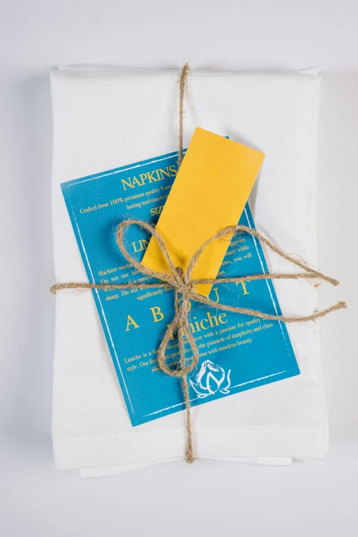 a book wrapped in twine and tied with twine, inspired by Eden Box, private press, yellow and cyan color palette, service ticket close up, white sheets, abcdefghijklmnopqrstuvwxyz