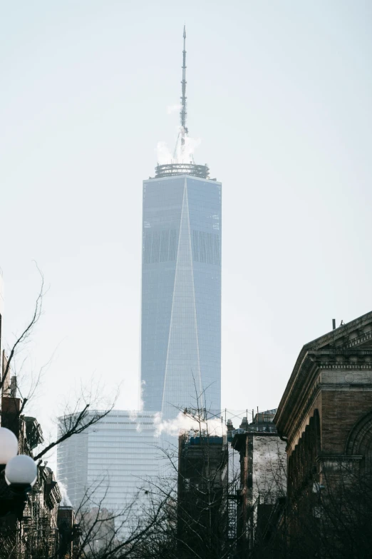 a street light in front of a tall building, by Nina Hamnett, trending on unsplash, world trade center twin towers, chimney with smoke, in new york, during the day