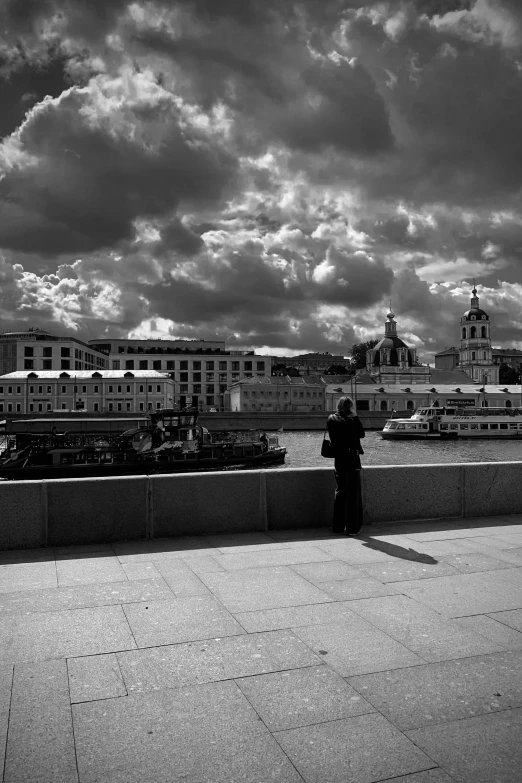 a black and white photo of a person on a bridge, inspired by Henri Cartier-Bresson, vorticism, in moscow centre, with dramatic sky, riverside, medium format