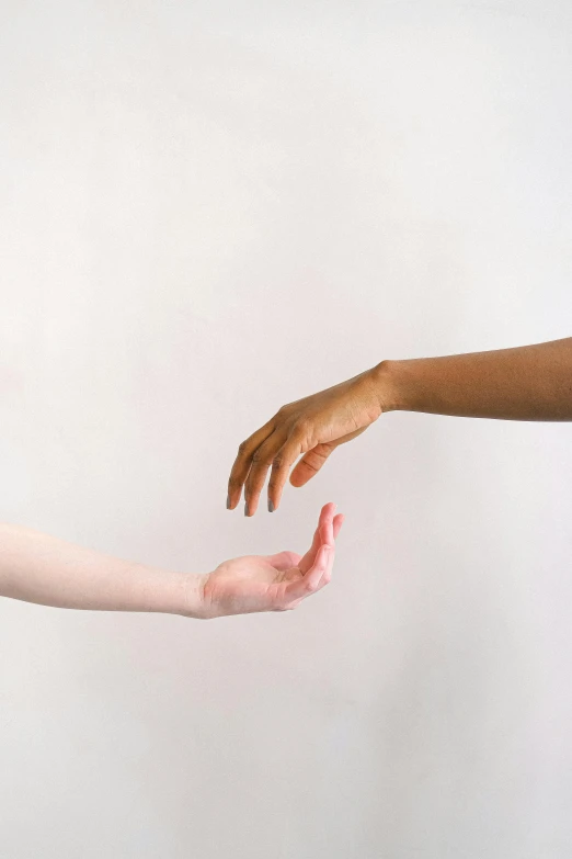 two hands reaching out towards each other, by Arabella Rankin, pexels, minimalism, plain background, mixed race, two women, light skin