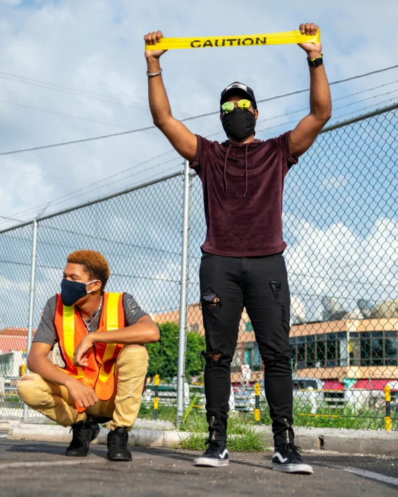 a man holding up a sign in a parking lot, pexels contest winner, black arts movement, two figures wearing gas masks, pride month, on a street race track, trending photo