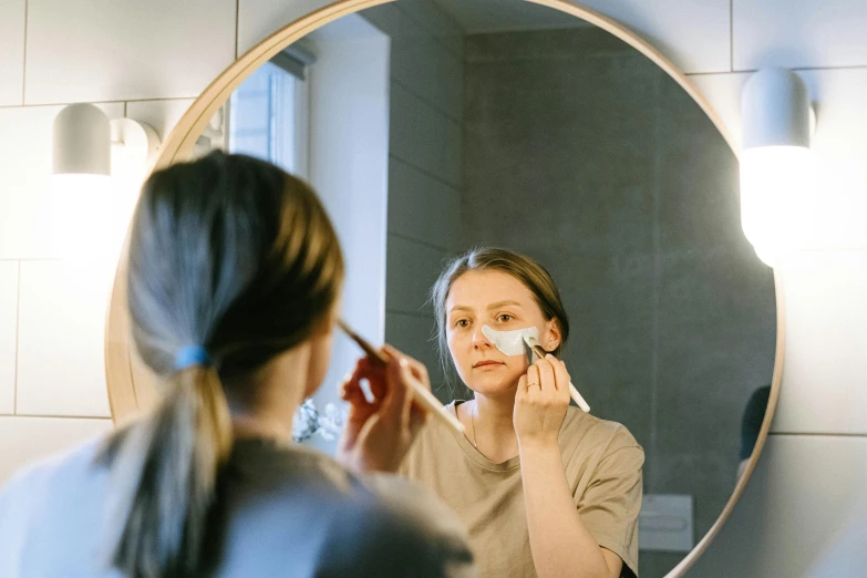 a woman brushes her teeth in front of a mirror, by Nicolette Macnamara, pexels contest winner, white facepaint, square facial structure, professional image, some of them use gask mask