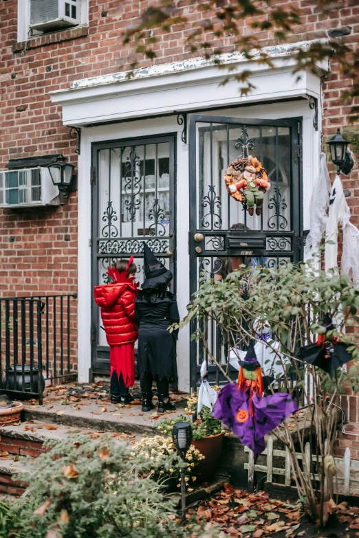 a couple of kids standing in front of a house, halloween decorations, new york times, about to enter doorframe, shot from a distance