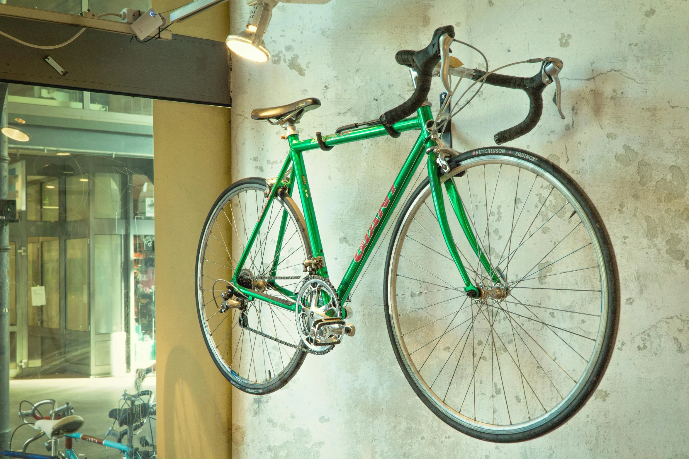 a green bike mounted to the side of a wall, unsplash, photorealism, hanging from the ceiling, 1990's photo, clubs, renzo piano