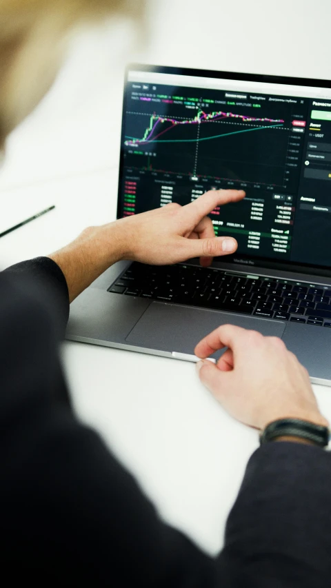 a man sitting at a desk using a laptop computer, pexels, analytical art, displaying stock charts, car trading game, low quality photo, - 9