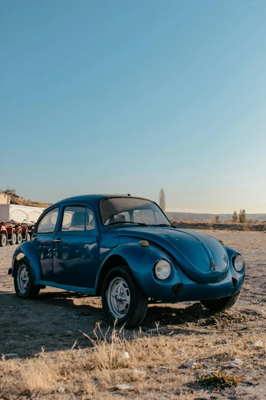a blue car sitting on top of a sandy beach, beetle-inspired, profile image, at golden hour, peruvian looking
