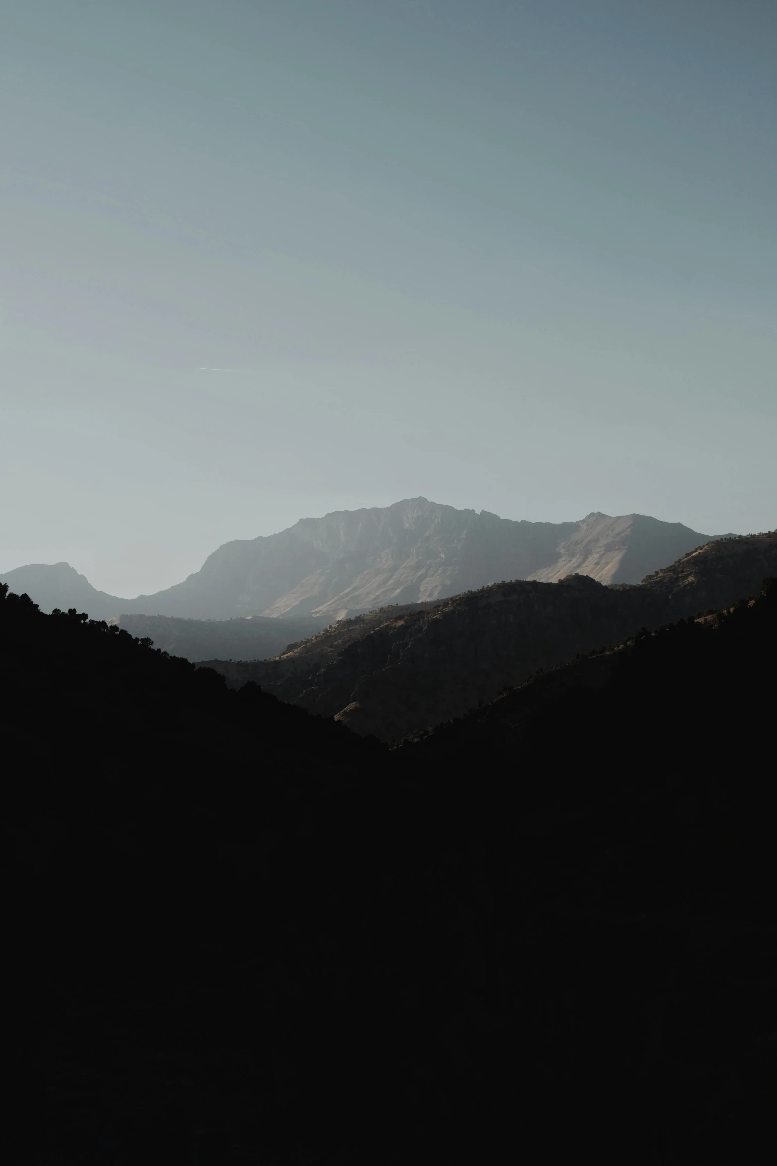 the silhouette of a person standing on top of a mountain, unsplash contest winner, minimalism, morocco, muted dark colors, seen from a distance, mountain ranges