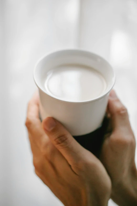 a person holding a cup of coffee in their hands, by Emily Shanks, pale milky white porcelain skin, soymilk, promo image, multiple stories