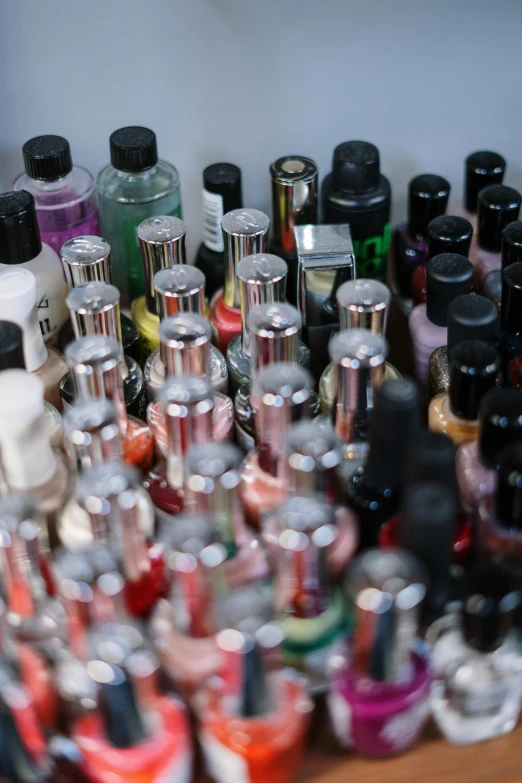 a wooden table topped with lots of bottles of nail polish, by Everett Warner, unsplash, happening, close - up photo, photograph credit: ap, half image, journalism photo