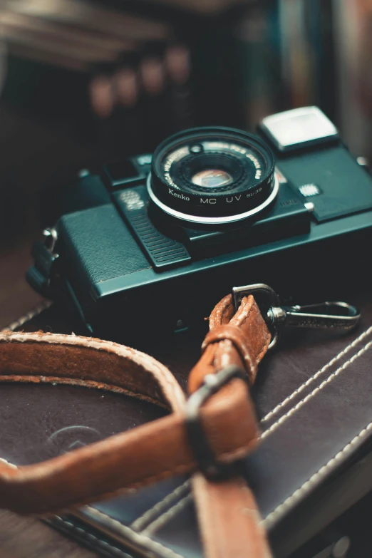 a camera sitting on top of a stack of books, leather straps, rugged details, unsplash 4k, expired film stock