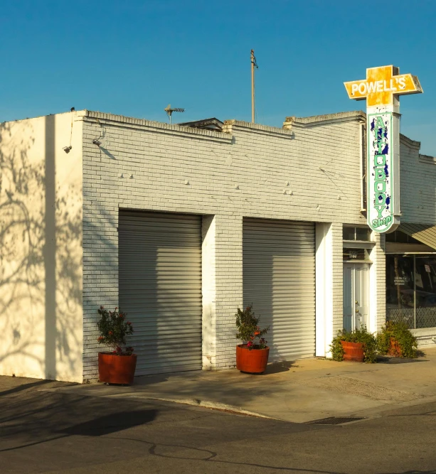 a white building sitting on the side of a road, storefront, los angelos, garage, ivy's