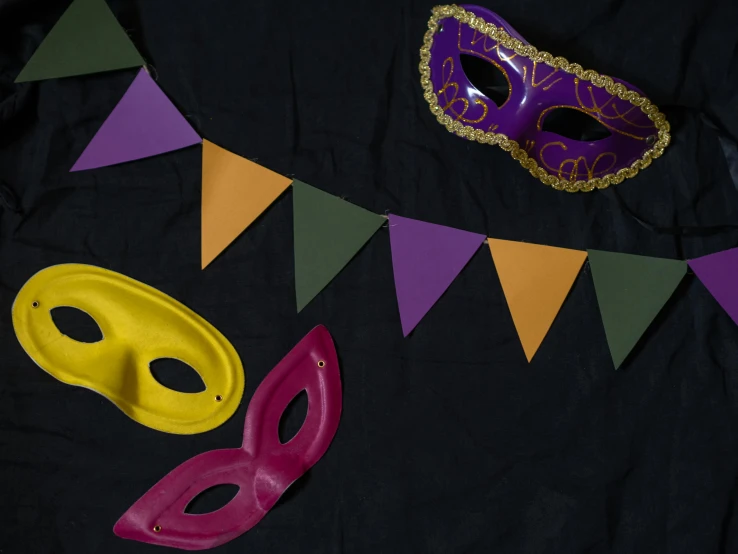 a couple of masks sitting on top of a table, inspired by Bernd Fasching, trending on unsplash, renaissance, yellow purple green black, red pennants, thumbnail, background image