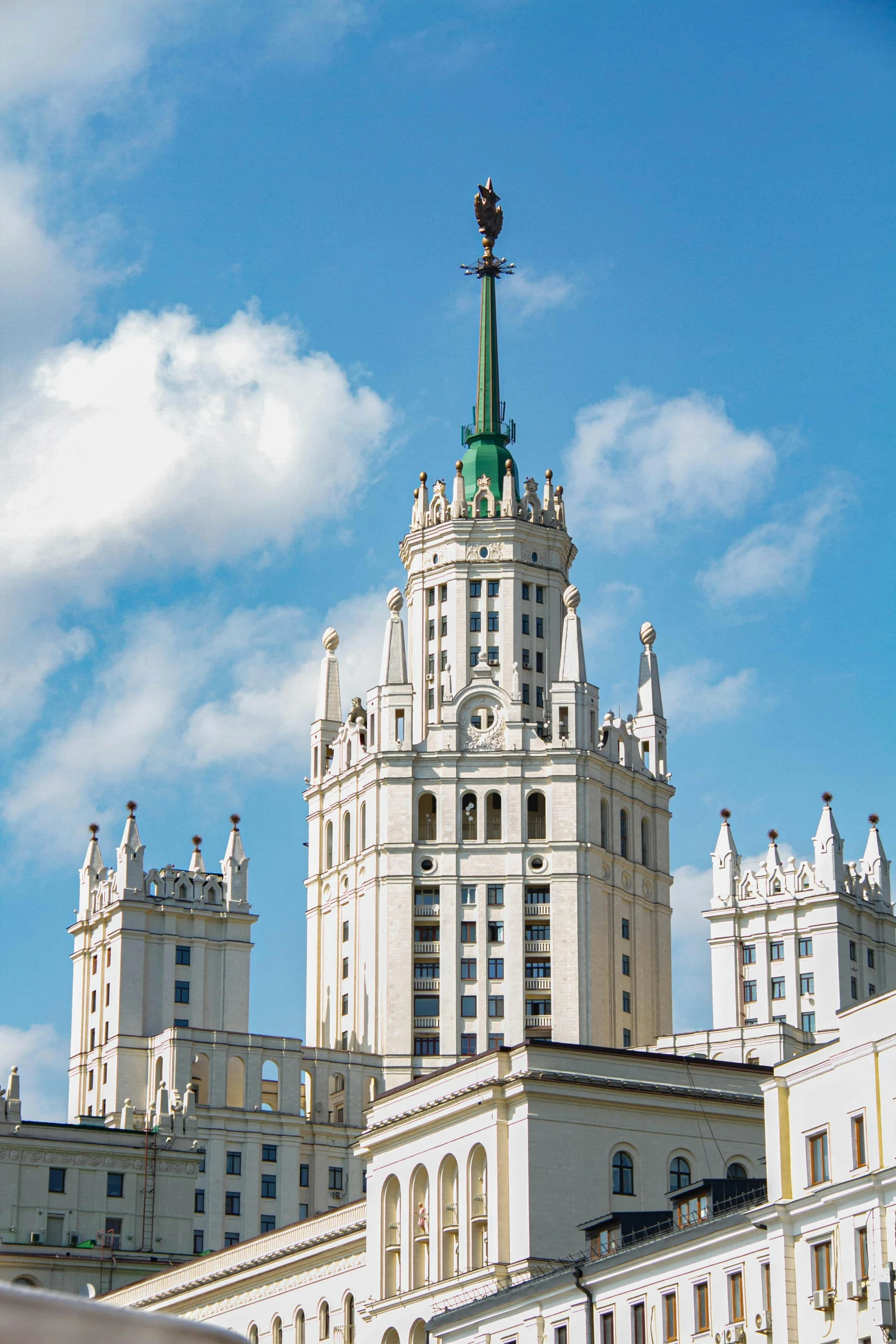 a large building with a clock on top of it, inspired by Fyodor Vasilyev, with stalinist style highrise, ivory towers, neo - gothic architecture, sky - high view