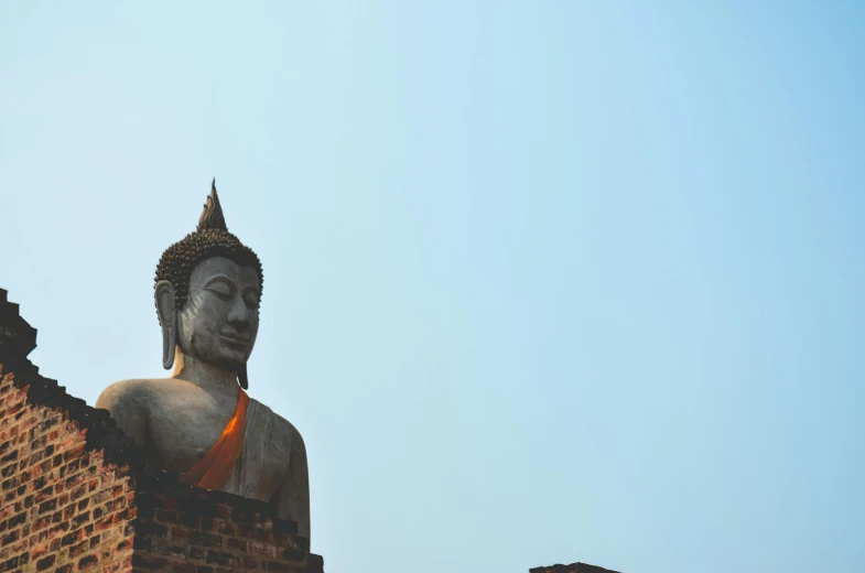 a statue sitting on top of a brick building, pexels contest winner, buddhist, background image, clear sky above, thawan duchanee