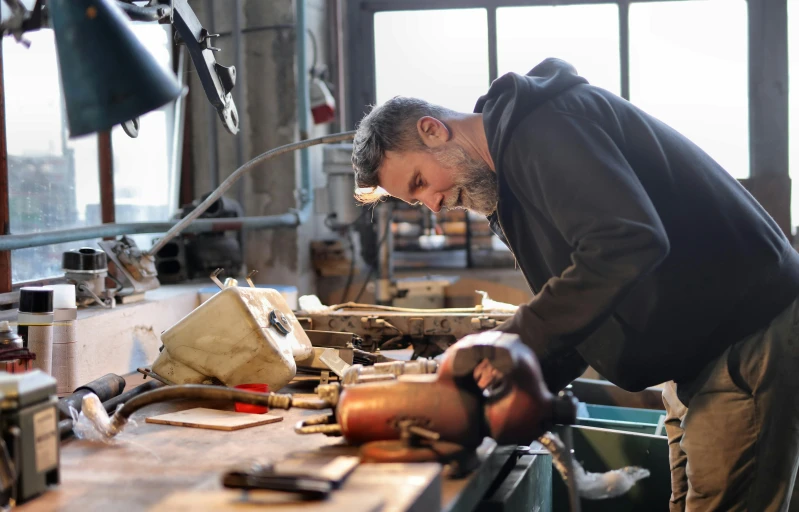 a man working on a piece of wood in a workshop, pexels contest winner, arbeitsrat für kunst, weathering armor plating, australian, made in bronze, people at work