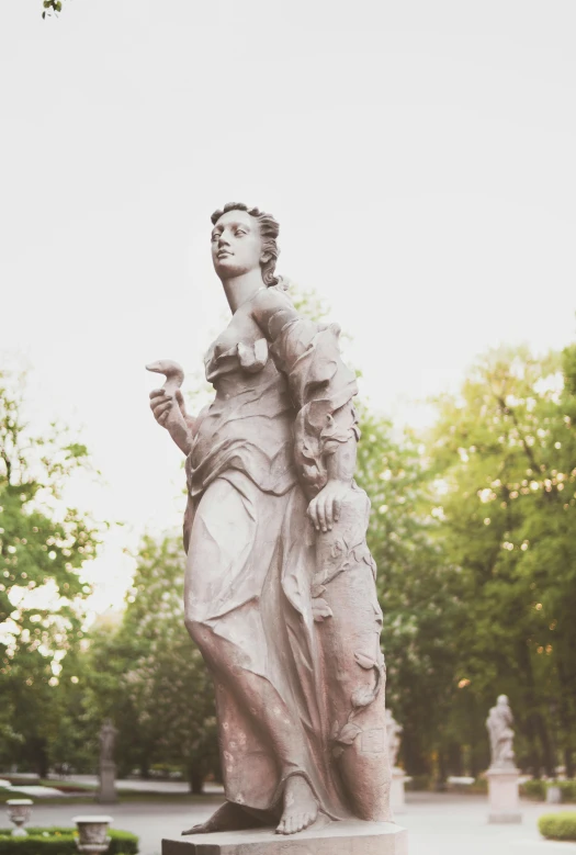 a statue sitting in the middle of a park, by Adam Marczyński, unsplash, neoclassicism, the goddess artemis smirking, evening time, russian neoclassicism, album cover