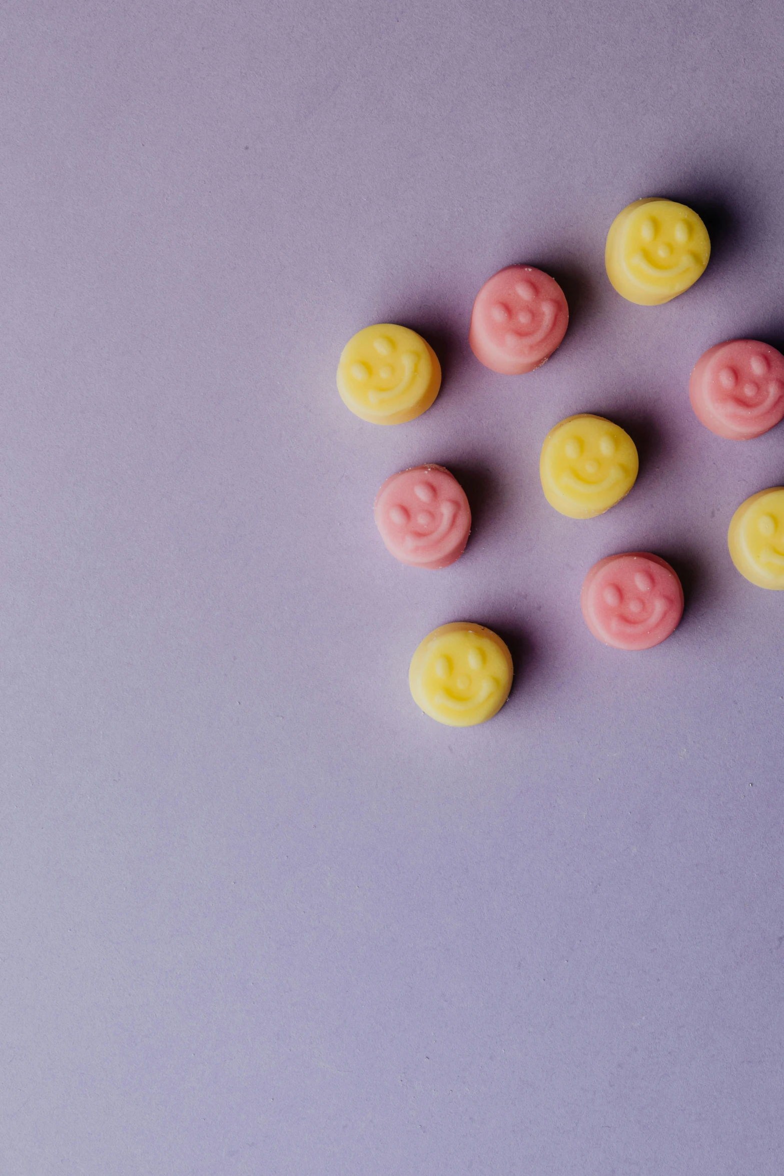 a bunch of candy sitting on top of a purple surface, smiley profile, muted pastel colors, dimples, pink and yellow