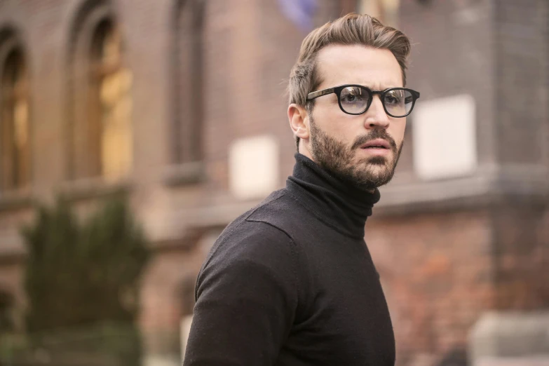 a man wearing glasses standing in front of a building, inspired by George Jamesone, pexels contest winner, renaissance, black turtle neck shirt, beard stubble, attractive girl, square masculine jaw