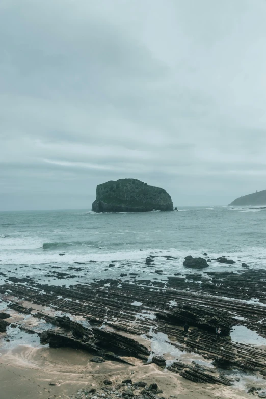 a man standing on top of a beach next to the ocean, inspired by Thomas Struth, unsplash, renaissance, icelandic landscape, big overcast, island with cave, today\'s featured photograph 4k