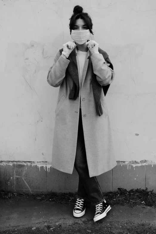 a black and white photo of a woman covering her face, inspired by August Sander, unsplash, bauhaus, ( ( wearing a long coat ) ), lil peep, single character full body, androgynous male