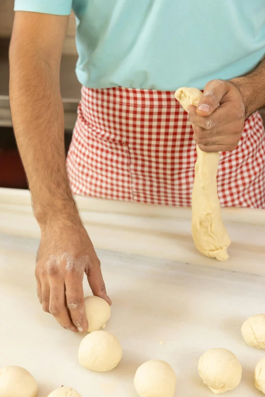 a man rolling dough into balls on a table, inspired by Michelangelo Buonarotti, dribble, long neck, no cropping, large tall, cast