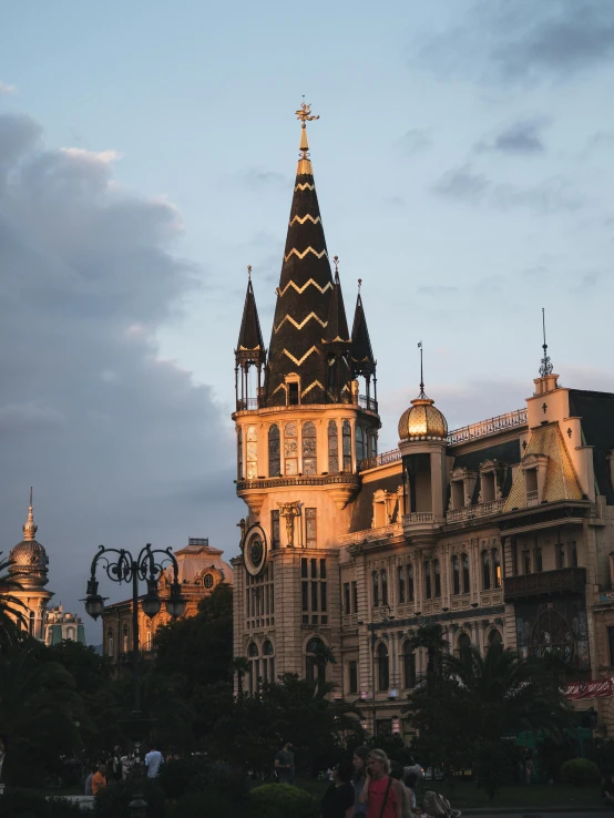 a large clock tower sitting in the middle of a city, inspired by Vasily Surikov, unsplash contest winner, art nouveau, golden hues, black domes and spires, summer evening, square