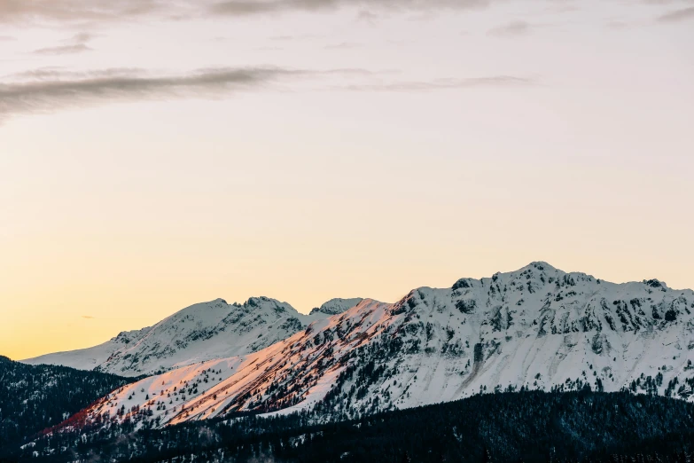 a couple of people riding skis on top of a snow covered slope, by Carey Morris, trending on unsplash, minimalism, sunset panorama, distant mountains lights photo