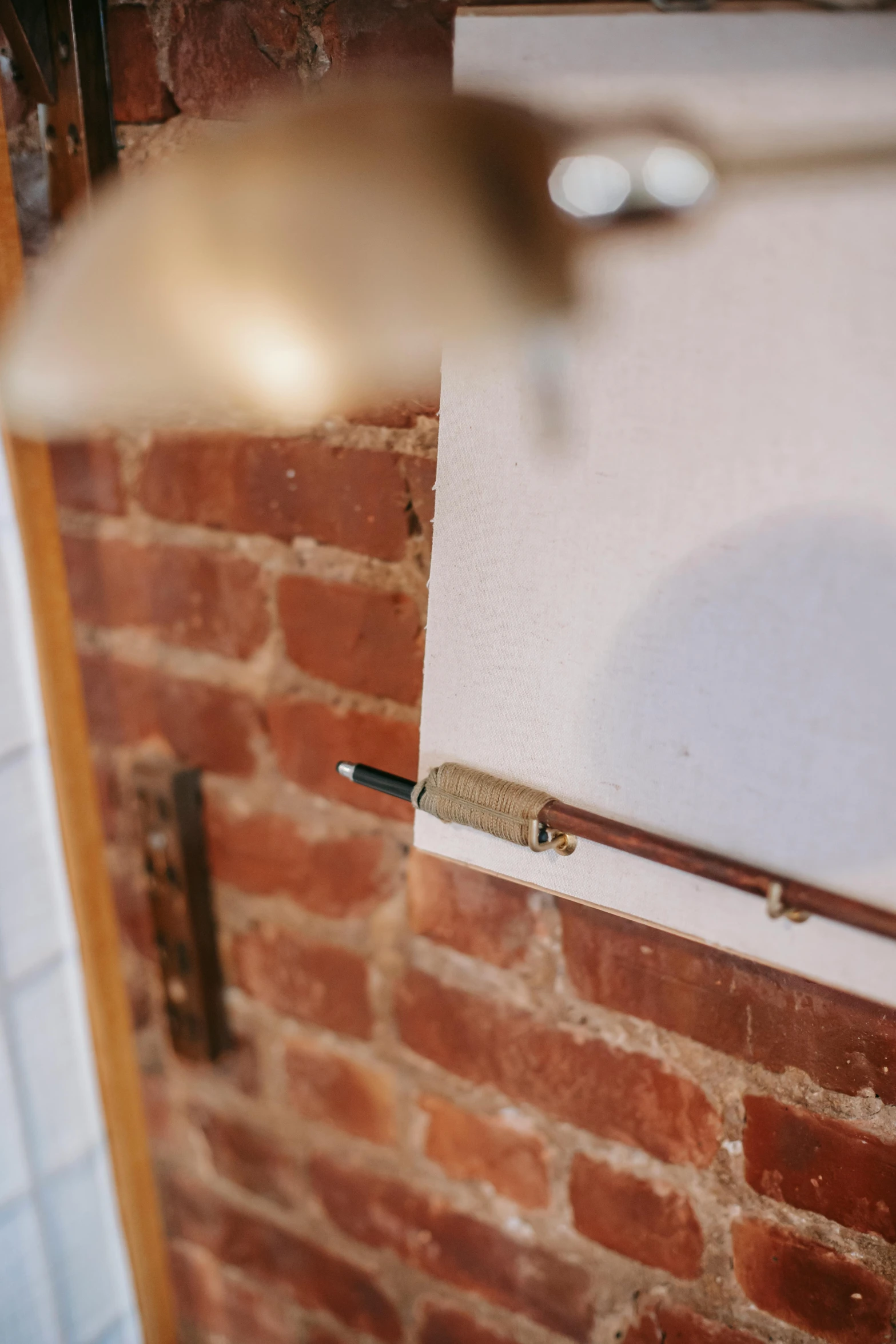 a close up of a light on a brick wall, inspired by Rube Goldberg, unsplash, kinetic art, copper and brass, long trunk holding a wand, gallery display photograph, hanging scroll