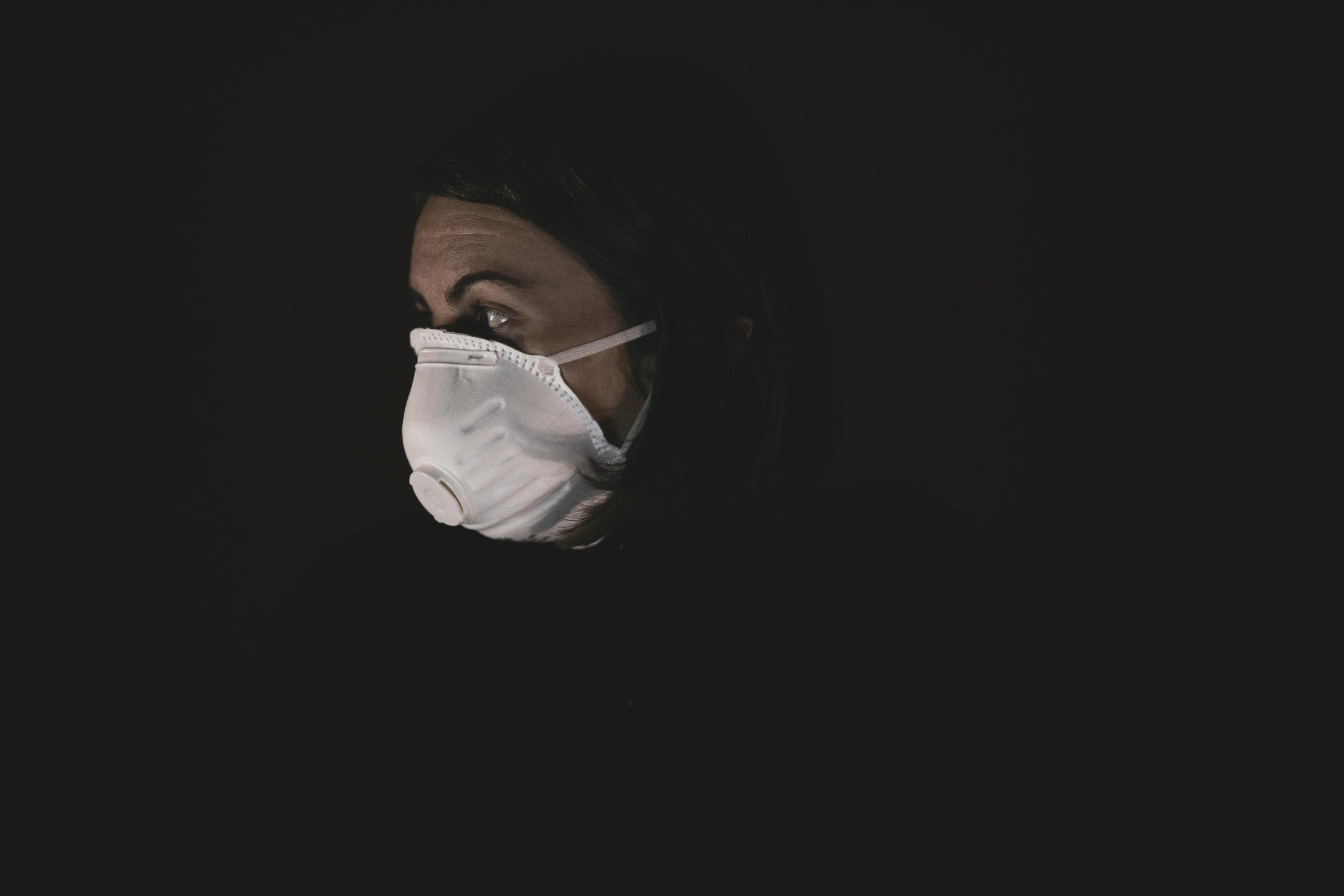 a woman wearing a face mask in the dark, a black and white photo, pexels, healthcare worker, polluted, plain background, avatar image