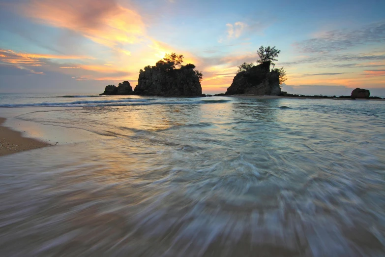 a large body of water sitting on top of a sandy beach, a picture, at the sunset