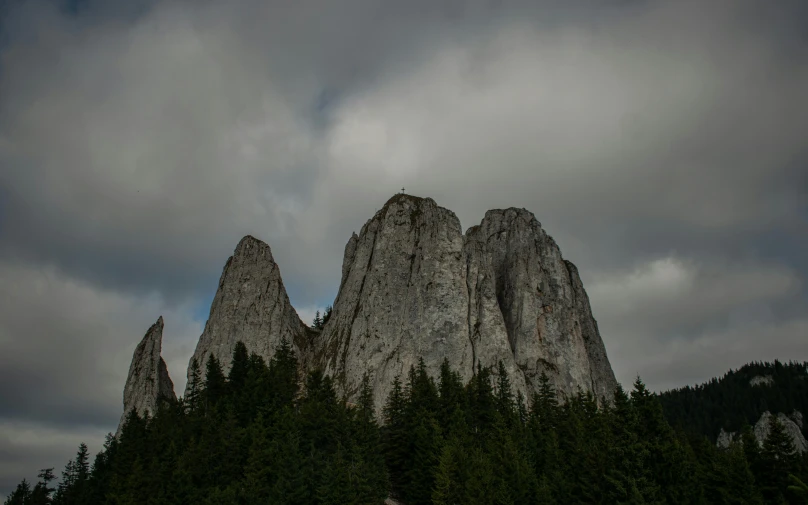 a bride and groom standing in front of a mountain, an album cover, by Adam Szentpétery, pexels contest winner, romanticism, monolithic granite spikes, gray clouds, transylvania, three hairy neanderthal people