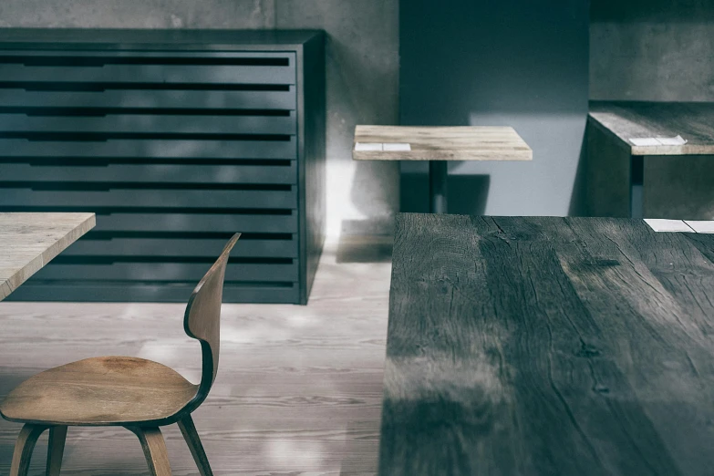 a wooden table sitting on top of a wooden floor, inspired by Peter Zumthor, trending on unsplash, minimalism, very smoky paris bar, anthracite, large chest, soft grey and blue natural light